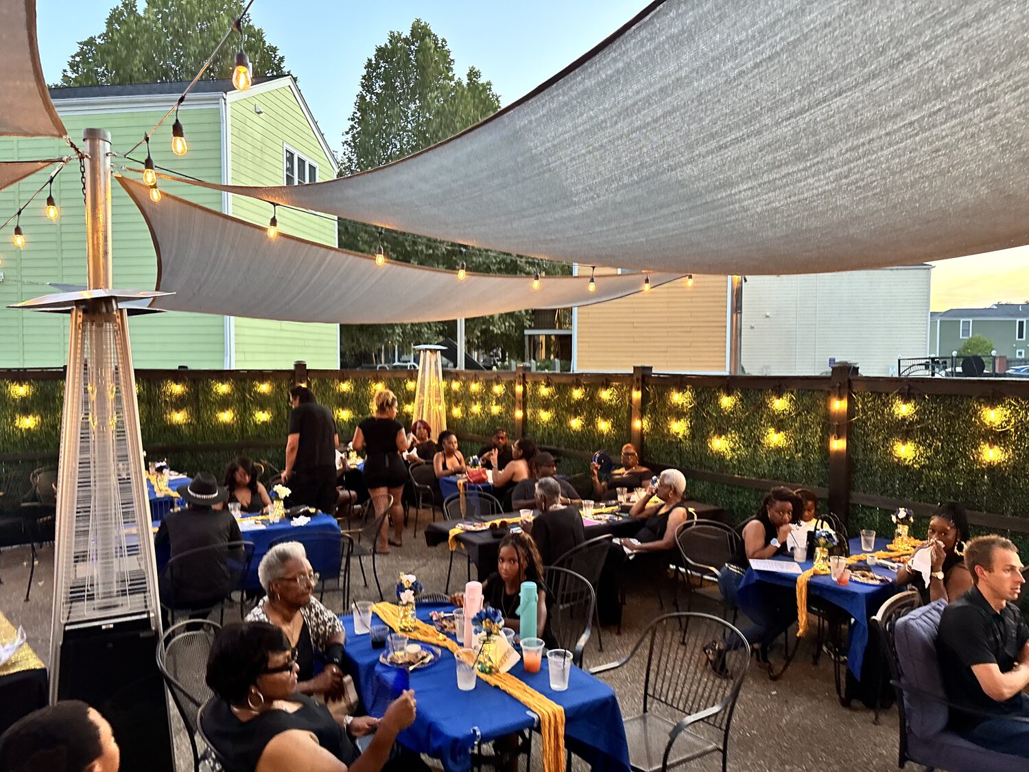 Friends around patio tables beneath string lights at The District